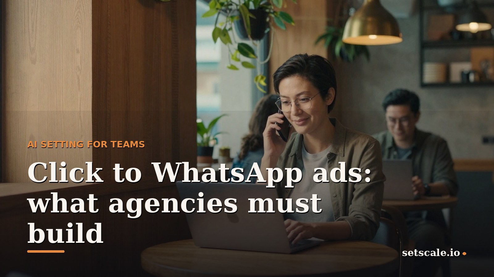 Man in his early thirties running paid campaigns for several client accounts, short dark hair, thin glasses, olive green shirt, seated at a warm wooden table in a small agency office with hanging plants and a brass pendant lamp, phone in one hand and laptop open, late afternoon light