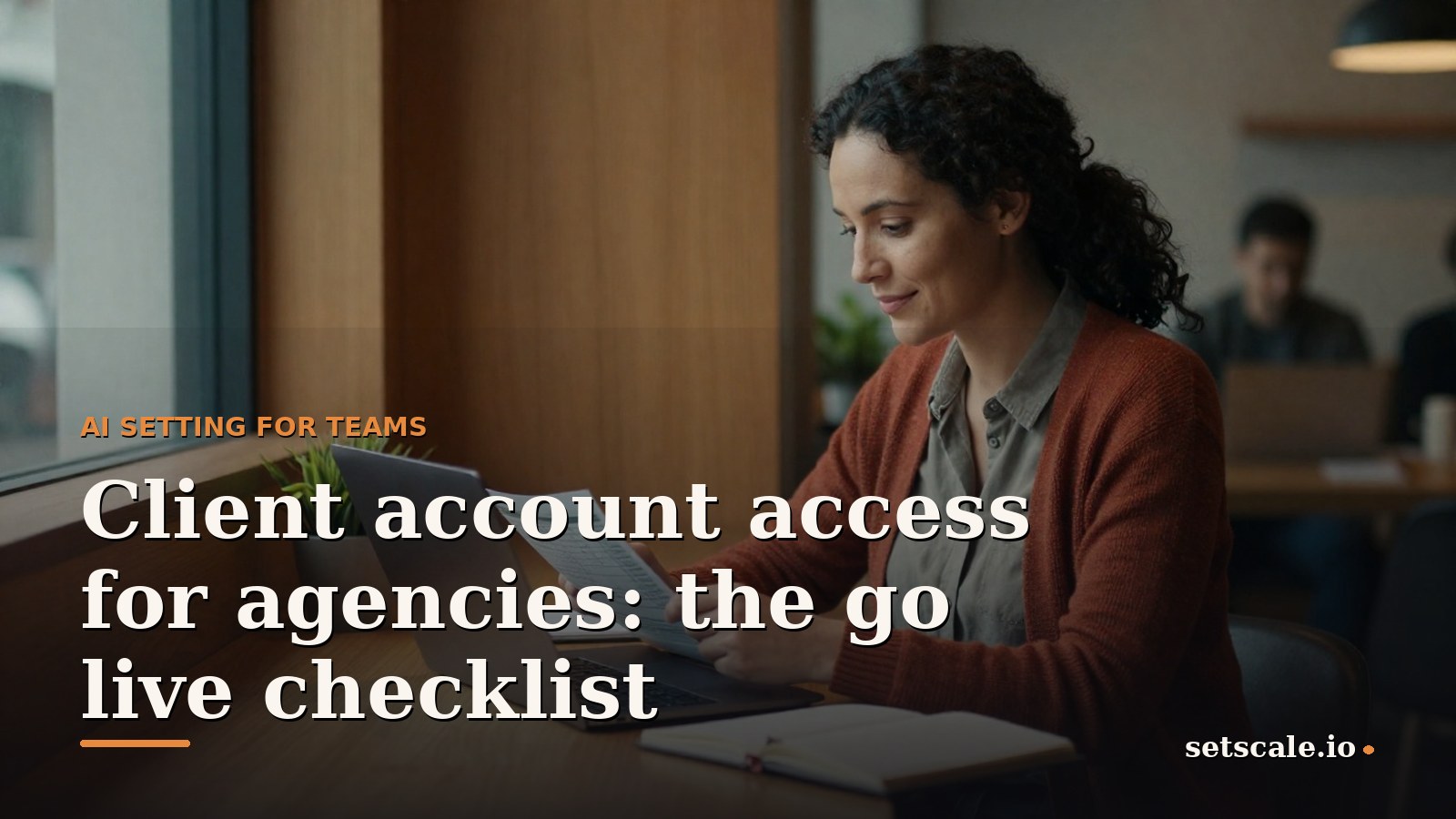 Woman around thirty with dark curly hair tied back and a rust coloured knit cardigan, sitting at a warm oak desk in a small agency office with a green plant and an open notebook, reviewing an account checklist on a laptop in soft window light